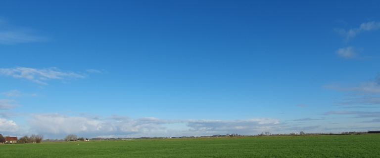 Het Hogeland, hier afgebeeld als een grasveld en blauwe lucht.